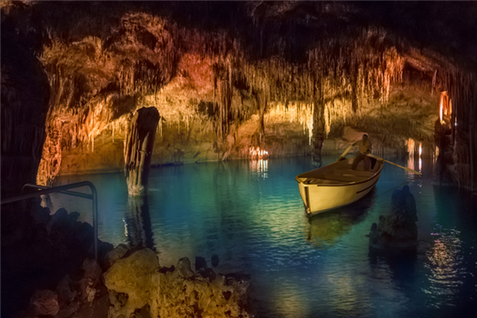 rowboat on the underground cave lake martel of cuevas del drach, surrounded by stalactites