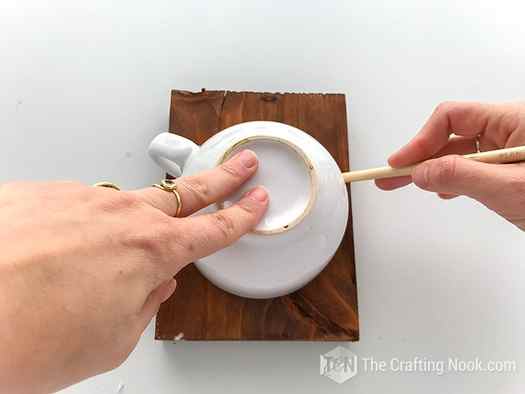 Using a large cup to trace a circle on the stained wood