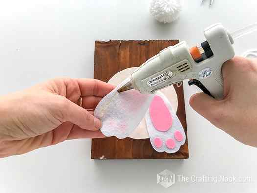 Gluing the bunny feet on the wooden easter signs over the white circle