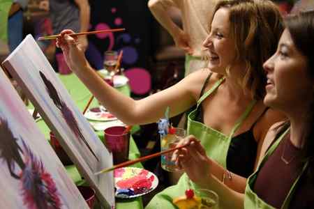 Two girls laughing at a paint and sip party with Paint Night