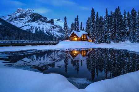 A small cabin with lights on at dusk in the winter at Emerald Lake, Canada