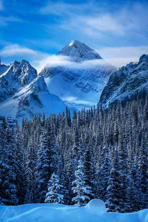 a vertical winter scene of mountains and clouds and snow in Canada