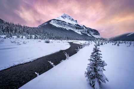 A brilliant sunrise over snow-covered mountains and a river in a winter scene in Canada