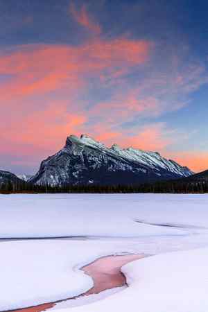 A winter scene of a snow-covered Vermillion Lake in front of Mount Rundle, Canada