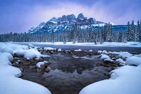 Castle Mountain reflected in the water surrounded by snow in the winter
