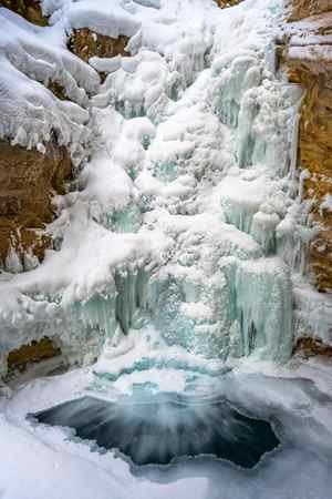 A winter scene of a frozen waterfall at Johnston Canyon in Canada