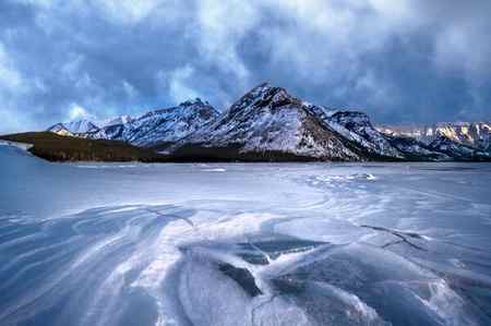 Ice formations in Lake Minnewanka in front of the snow-covered mountains in winter