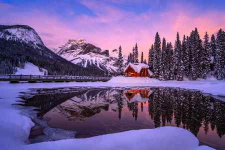 A small cabin with lights on during sunset in the winter over Emerald Lake, Canada