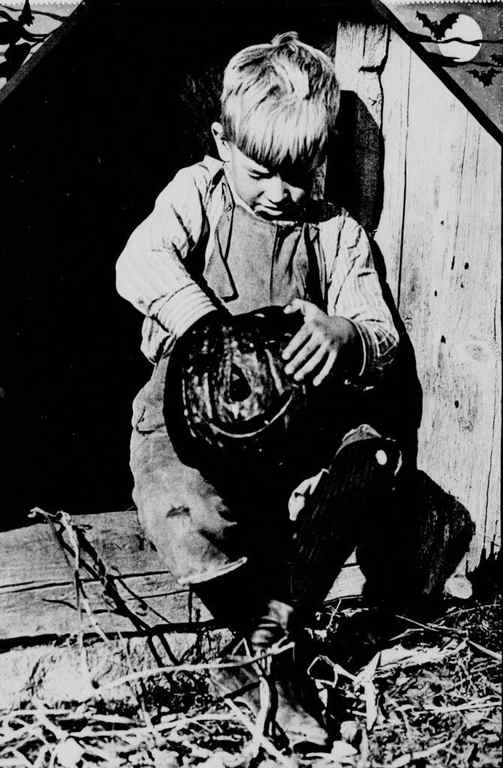 image detail from a 1915 New York newspaper of a boy dressed in overalls carving a pumpkin. 