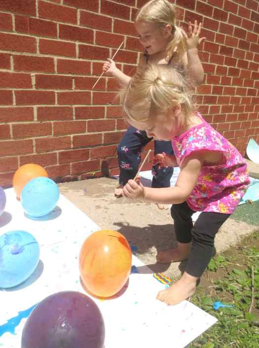 Image shows two kids making balloon painting outside. Idea from Growing a jeweled rose