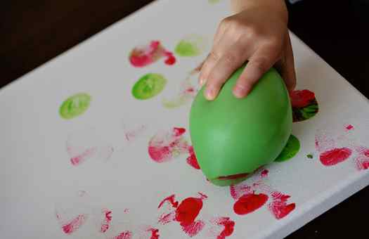 Image shows a kid holding a green balloon to create art. Idea from Glued to my crafts blog.