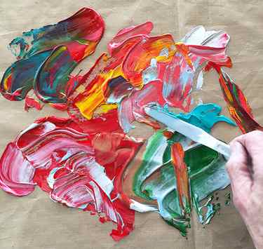 Spreading acrylic paint on a craft sheet for making paint skins
