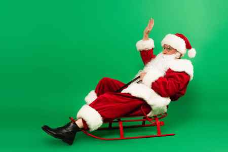 Санта Клаус Машет Рукой Сидя Санях Зеленом Фоне — стоковое фото