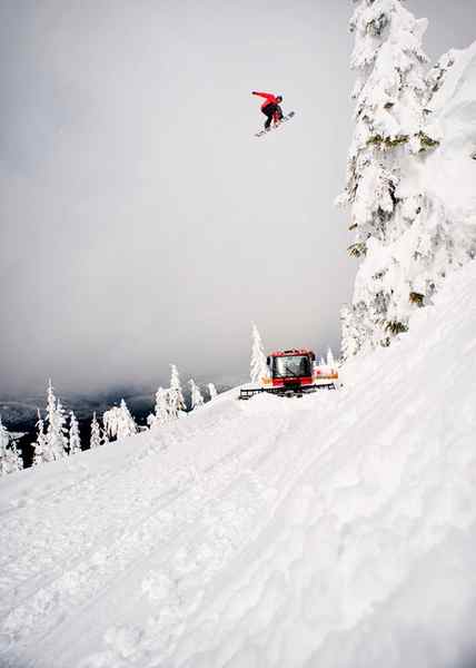 Snowboarder jumping over a snow plow