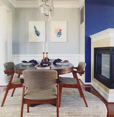  Two abstract paintings serve as the focal point in a mid century dining room 
