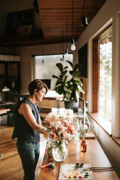 Artist Emma Fuss in her kitchen with a vase of flowers.