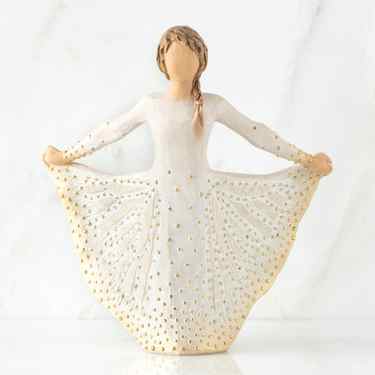 Angel figurine in white and gold beaded dress with dark hair braid