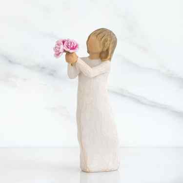 Front side view of girl with light brown hair holding out pink flowers with both hands