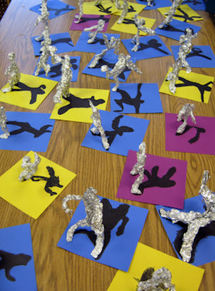 Shadow art - small pieces of paper with aluminum foil statues on top with shadows outlined in marker