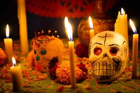 sugar skulls and candles on ofrenda