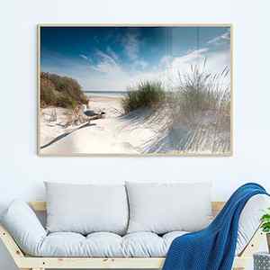 Beach artwork hanging over a wood and linen daybed. This white room is decorated with straw hats on the wall, round jute poufs and a dark blue patterned rug.