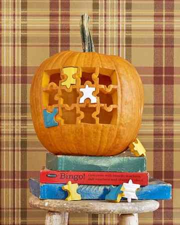 pumpkin carved with jigsaw puzzle design with painted removable pieces beside pumpkin with painted dartboard design