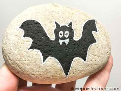 Drawing around the halloween bat rock stone with a white posca pen