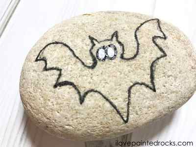 Painting the Outline of the halloween bat onto the stone