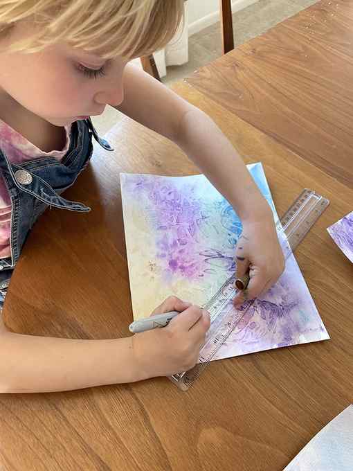Child drawing constellations on watercolor painting