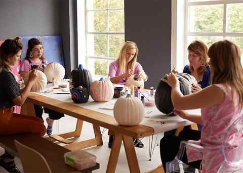 Six Hallmark artists share a table to paint pumpkins