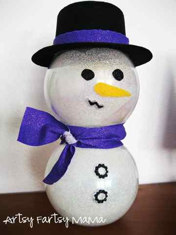 glittery snowman made of two glass bowls with a glittering blue scarf and a top hat with a glittering blue band