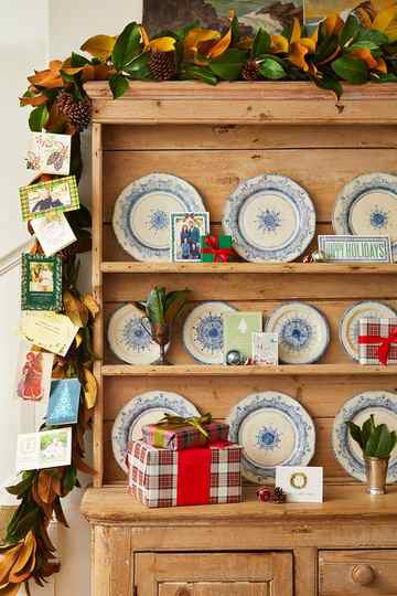 a shelf with plates bowls and christmas cards on display