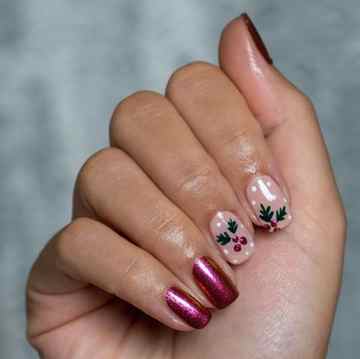 a hand with painted fingernails in a holly berry holiday motif
