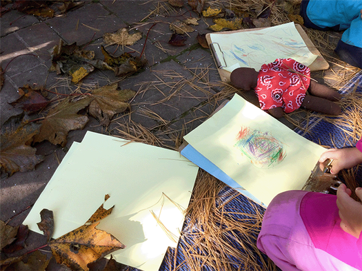 Children drawing fall leaves outside.