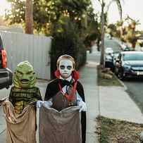 Young Siblings Dressed In Halloween Costumes During Trick-or-treat by Cavan Images